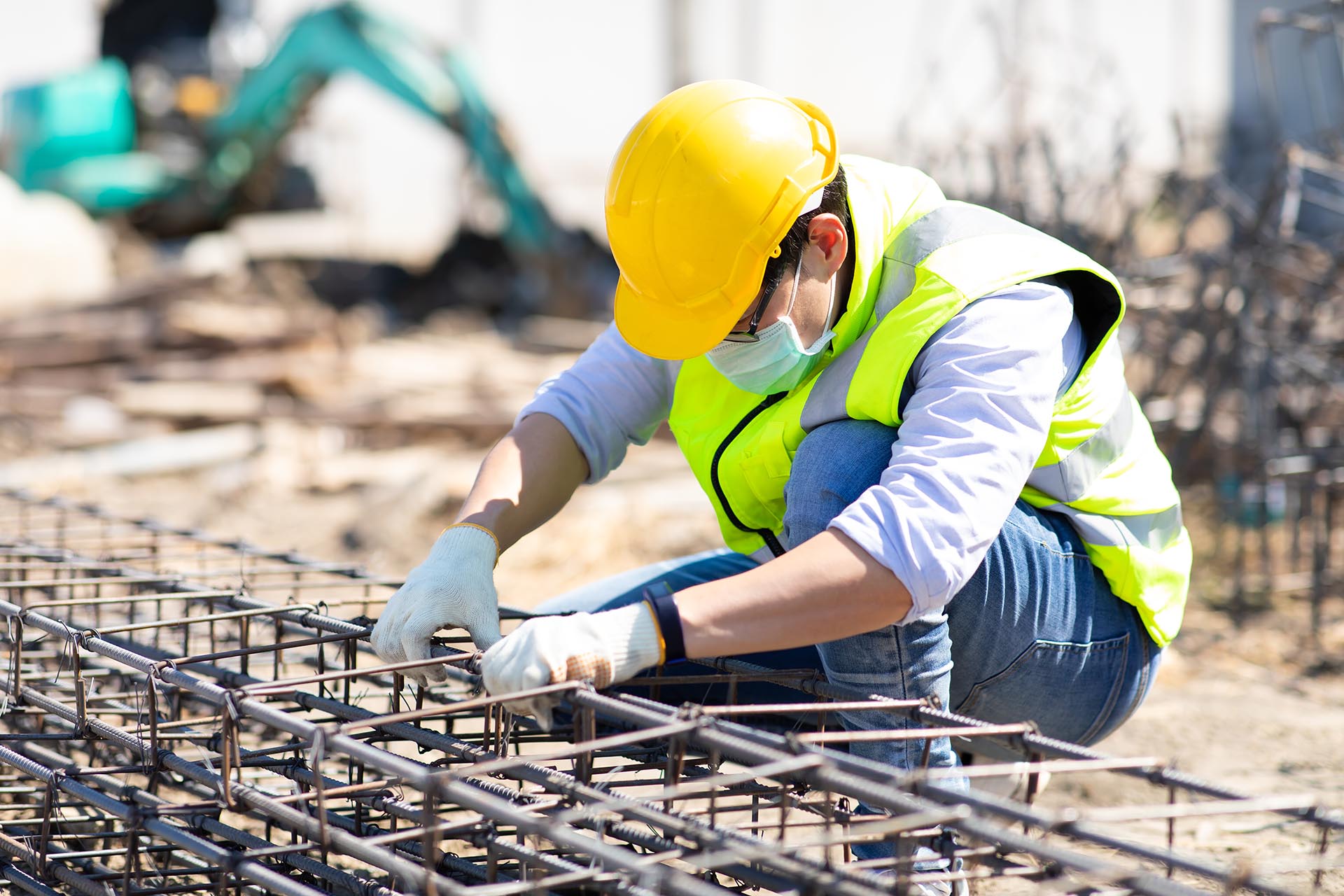 Asian construction worker on building site. fabricating steel reinforcement bar. wearing surgical face mask during coronavirus and flu outbreak